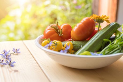Fresh colorful vegetables in a bowl, raised in the own garden. Tomatoes, zucchini, flowers and herbs.