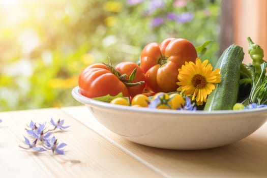 Fresh colorful vegetables in a bowl, raised in the own garden. Tomatoes, zucchini, flowers and herbs.