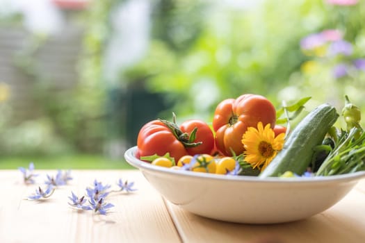 Fresh colorful vegetables in a bowl, raised in the own garden. Tomatoes, zucchini, flowers and herbs.