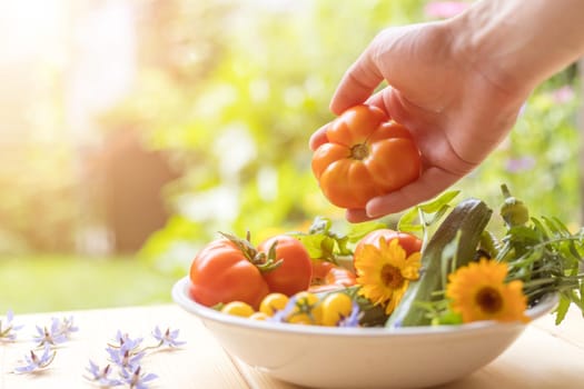 Fresh colorful vegetables in a bowl, raised in the own garden. Tomatoes, zucchini, flowers and herbs.