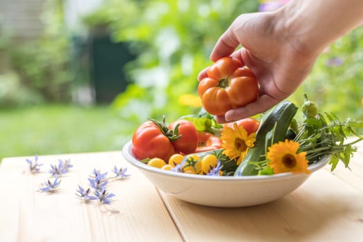 Fresh colorful vegetables in a bowl, raised in the own garden. Tomatoes, zucchini, flowers and herbs.