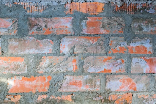 Red brick wall old dirty with peeling plaster. Brickwork. Background. Texture. Close-up