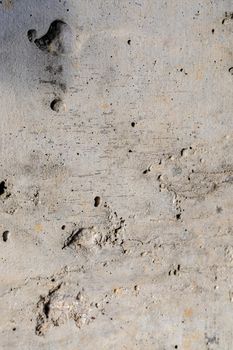 Background image of a rough concrete pour. Modern finishing of concrete walls. Holes, dents, scratches. Close-up