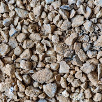 Gravel texture. Small and medium stones, pebbles of many shades of gray, white, brown, yellow, mixed with sand. Background from wet oval sharp stones. The texture of small stones for paving the road.