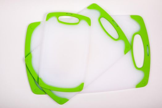 Set of white kitchen cutting boards with green handles for cooking. For cutting food, vegetables, meat, fish. Durable, professional, white plastic.