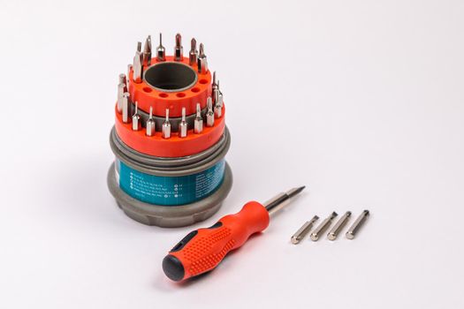 A set of working tools with a screwdriver and bits for repair, in an open plastic box with iron bits, inside a screwdriver.