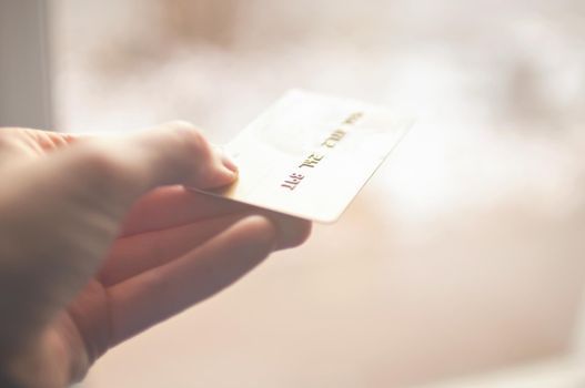 bank card of gold color in hands on a background of sunlight