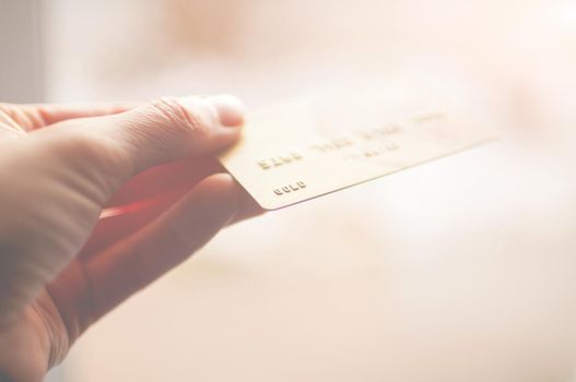 bank card of gold color in hands on a background of sunlight