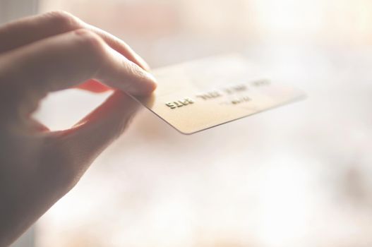 bank card of gold color in hands on a background of sunlight