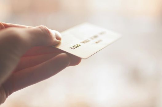 bank card of gold color in hands on a background of sunlight