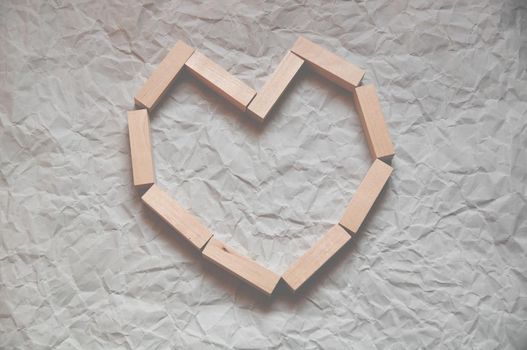 background of crumpled craft paper with wooden rectangles laid out in the shape of a heart in a minimalist style