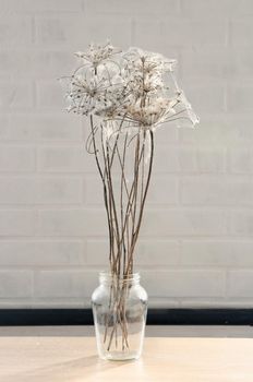 dry flowers braided with cobwebs on a brick wall background