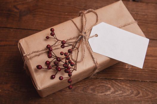 gift wrapped in craft paper on top of a flower tied with twine, which lies on a wooden table