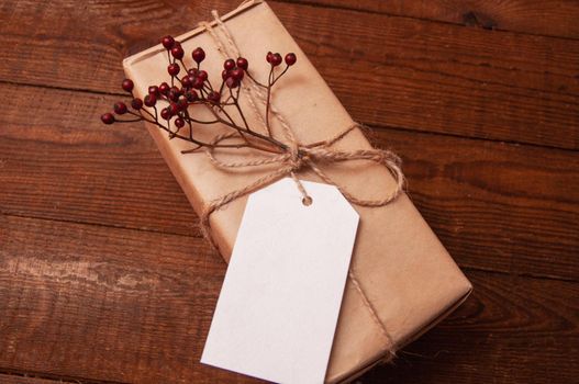 gift wrapped in craft paper on top of a flower tied with twine, which lies on a wooden table