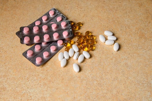 amber, pink and white capsules on a table with a pattern of sand