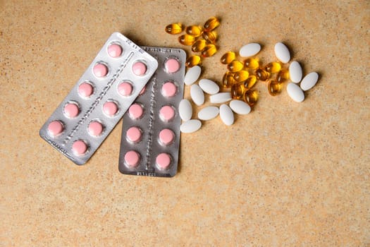 amber, pink and white capsules on a table with a pattern of sand