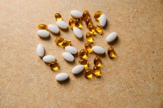 Vitamin D and fish oil capsules randomly lie on the background