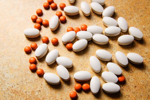 orange and white pills randomly lie on the background of sand countertops