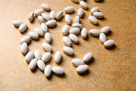 vitamin D pills lie chaotically against a sand countertop