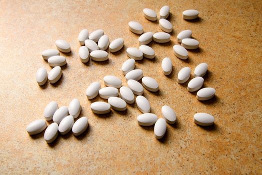 vitamin D pills lie chaotically against a sand countertop