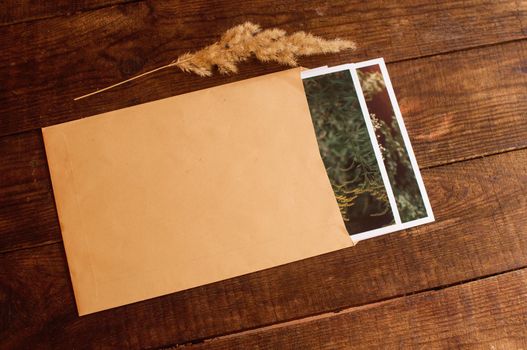 photos are enclosed in a beige envelope, located on a brown wooden table