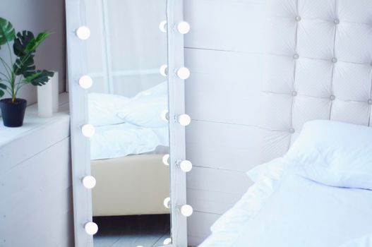bouquet of flowers on the bed and a mirror with light bulbs