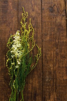 Floral colorful yellow bouqet wildflowers pattern on wooden background.