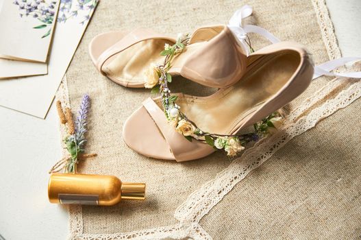 wedding shoes on a linen tablecloth table with a wreath of flowers for hair