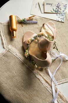 wedding shoes on a linen tablecloth table with a wreath of flowers for hair