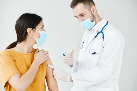 a patient in a medical mask looks at a doctor with a syringe in his hand vaccination infection. High quality photo