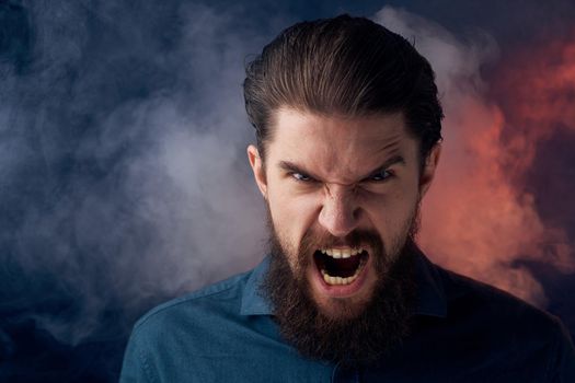 Emotional bearded man angry look shirt smoke in the background. High quality photo