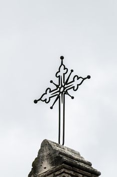 iron crucifix placed above a church on a gray day