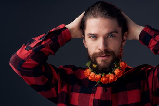 an elegant man in a plaid shirt flowers in a beard close-up dark background. High quality photo