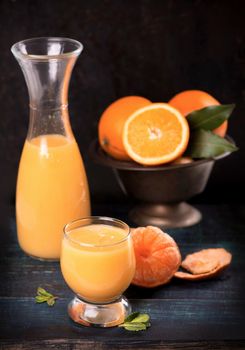 glass of fresh orange juice with fresh fruits on wooden table