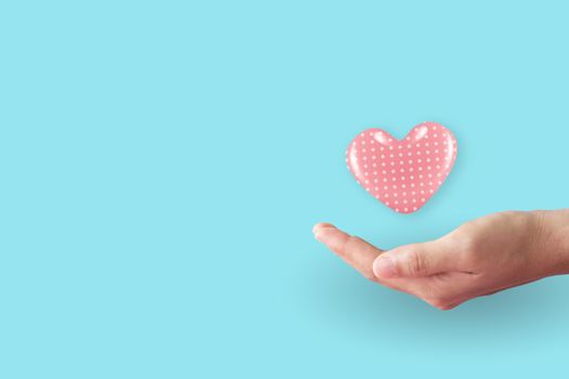 Close up of woman hands with heart with clean pastel background. Valentine's Day Love and care concept.