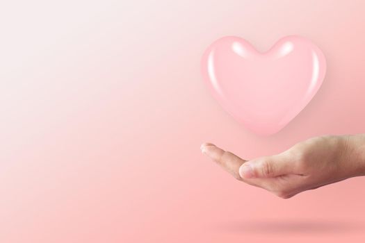 Close up of woman hands with heart with clean pastel background. Valentine's Day Love and care concept.