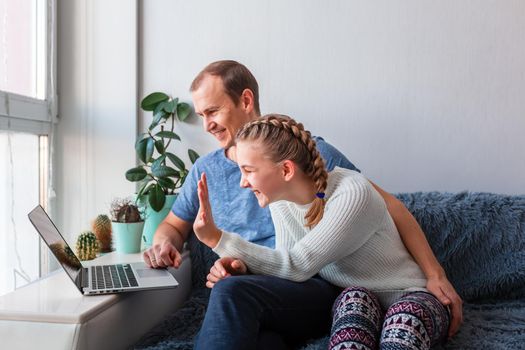 Father and daughter having video call with grandparents on laptop during covid quarantine lockdown. Stay at home, distance communication concept