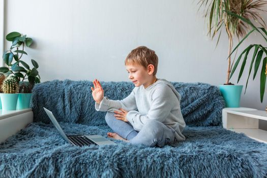 Little school boy having video call, online class on laptop during covid quarantine lockdown. E-learning, distance studying, distance communication concept