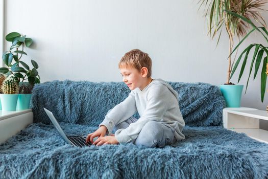 Little school boy having video call, online class on laptop during covid quarantine lockdown. E-learning, distance studying, distance communication concept