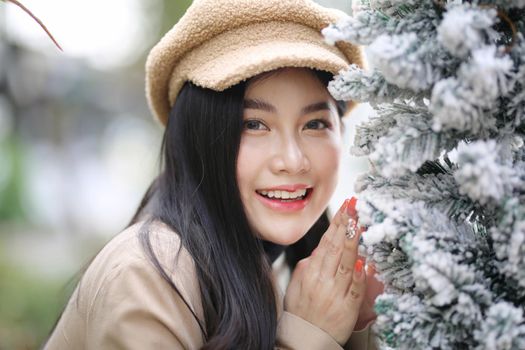 Portrait of young beautiful woman in winter clothes. while posing on snow background. Outdoor close-up photo of female model with romantic smile chilling in park in winter.