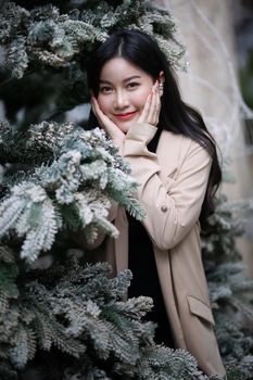 Portrait of young beautiful woman in winter clothes. while posing on snow background. Outdoor close-up photo of female model with romantic smile chilling in park in winter.