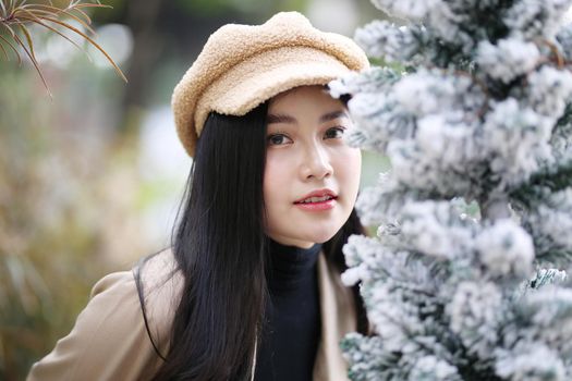 Portrait of young beautiful woman in winter clothes. while posing on snow background. Outdoor close-up photo of female model with romantic smile chilling in park in winter.