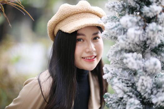 Portrait of young beautiful woman in winter clothes. while posing on snow background. Outdoor close-up photo of female model with romantic smile chilling in park in winter.