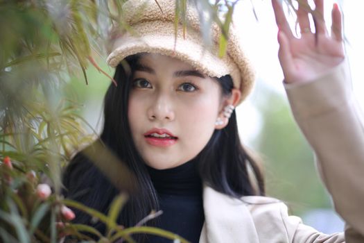 Portrait of young beautiful woman in winter clothes. while posing on snow background. Outdoor close-up photo of female model with romantic smile chilling in park in winter.