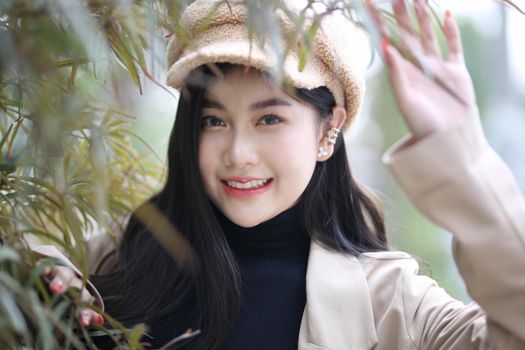 Portrait of young beautiful woman in winter clothes. while posing on snow background. Outdoor close-up photo of female model with romantic smile chilling in park in winter.