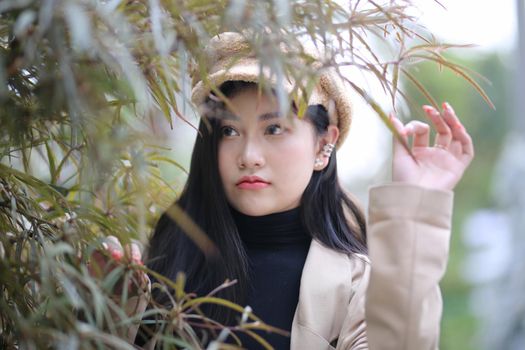 Portrait of young beautiful woman in winter clothes. while posing on snow background. Outdoor close-up photo of female model with romantic smile chilling in park in winter.