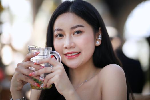 Beautiful young woman smiling while holding a glass of water at home. Lifestyle concept