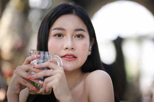 Beautiful young woman smiling while holding a glass of water at home. Lifestyle concept