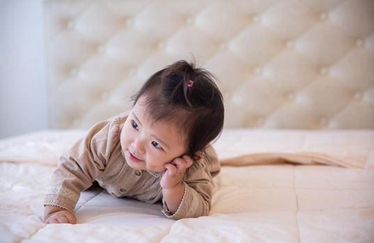 Portrait of a baby girl on the bed in bedroom