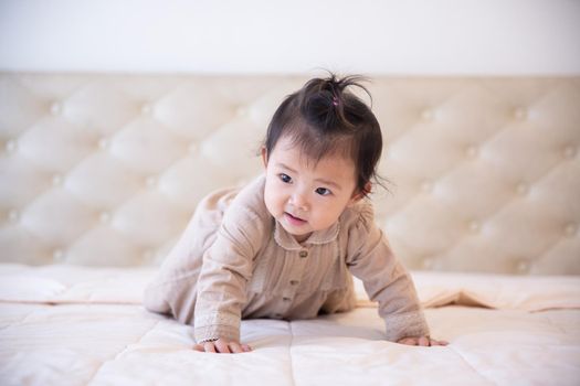 Portrait of a baby girl on the bed in bedroom